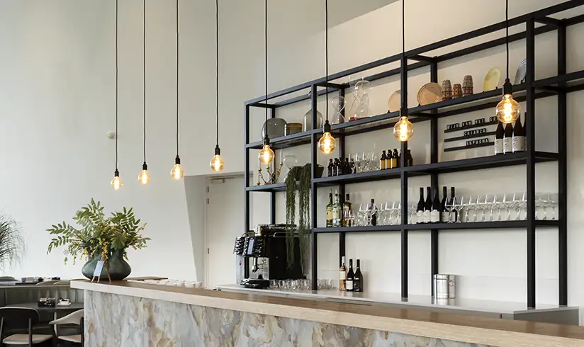 Een bar met een grote ijzeren kast erachter met daarin een koffiezetapparaat, wijnglazen en flessen